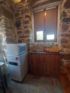 a kitchen with a white refrigerator and a stone wall at Πέτροκτιστο Σπίτι. Stone House in Ayía Kiriakí