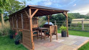 a wooden gazebo with a table and chairs at idyllic rural retreat - stunning 2 bed annex. in Wood Norton