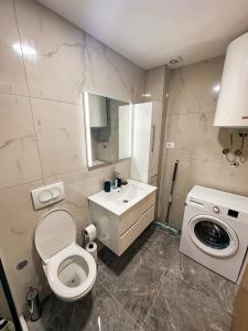 a bathroom with a toilet and a sink and a washing machine at Enigma Apartment in Ulcinj