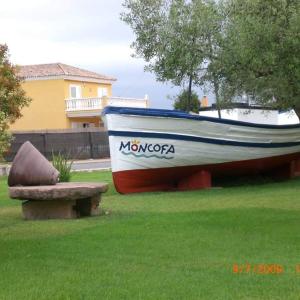 łódź siedząca w trawie obok ławki w obiekcie Apartamento al lado de la playa w mieście Moncófar