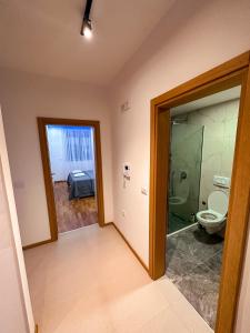a bathroom with a toilet and a glass door at Enigma Apartment in Ulcinj