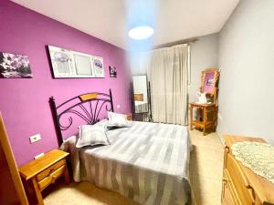 sypialnia z łóżkiem i fioletową ścianą w obiekcie Apartamento al lado de la playa w mieście Moncófar
