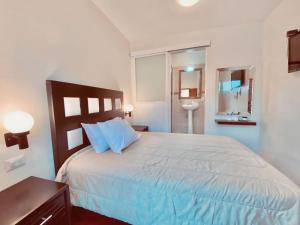 a bedroom with a large white bed with blue pillows at HOTEL PLAZA VASCO in Pátzcuaro