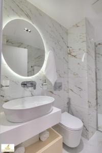 Baño blanco con lavabo y espejo en NORGE HOTEL, en Ksamil