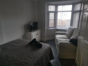 a bedroom with a bed and a couch and a tv at John Street in Shildon