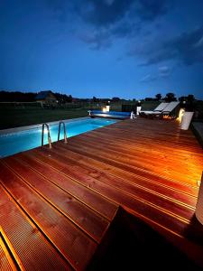 a wooden deck with a swimming pool at night at Domek letniskowy Jawor z basenem in Małdyty