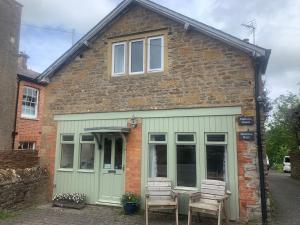 una casa con dos sillas sentadas fuera de ella en Mallows Cottage, en Sherborne