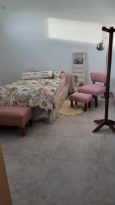 a bedroom with a bed and two pink chairs at Posada en Mendoza in El Challao
