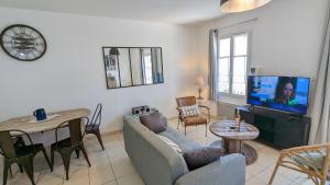 een woonkamer met een bank, een tafel en een tv bij Maison BARBADINE in Saint-Denis-dʼOléron