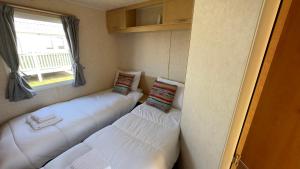 Habitación con 3 camas blancas y ventana. en Holiday Freedom, en Clacton-on-Sea