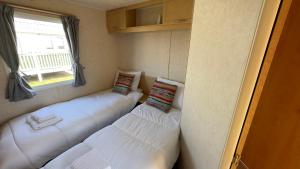 a room with three white beds in it with a window at Holiday Freedom in Clacton-on-Sea