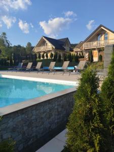 a swimming pool with lounge chairs next to a house at Domki Bajeczny Łan in Tylicz