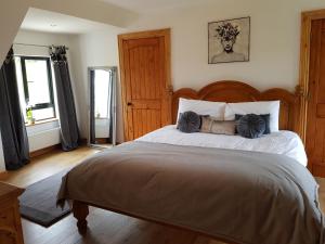 ein Schlafzimmer mit einem großen Bett mit einem hölzernen Kopfteil in der Unterkunft Atlantic Coast Holiday Home in Mountcharles