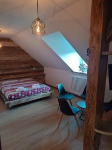 ein Schlafzimmer mit einem Bett und Stühlen im Dachgeschoss in der Unterkunft AlBy&B in Arnoldstein