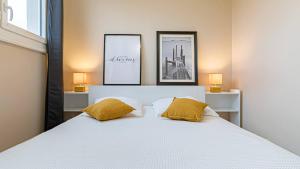 - une chambre avec un lit blanc et 2 oreillers jaunes dans l'établissement Les 70's Dutreix, à Limoges