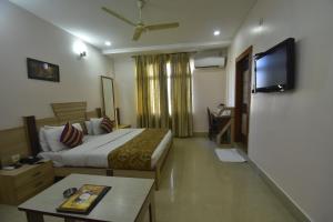 a hotel room with a bed and a flat screen tv at Hotel Royal Highness in Tinsukia