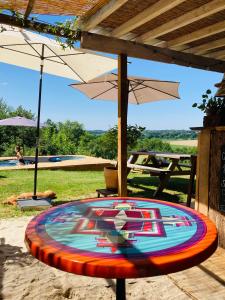 a painting on a table with an umbrella at Cabane Bivouac avec échelle à l'ombre des chênes in Idrac-Respailles