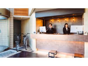 a man and a woman standing behind a counter at Hotel AreaOne Minamisoma - Vacation STAY 56244v in Minamisouma