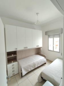 a bedroom with two beds and white cabinets and a window at Luan's House in Pozzallo