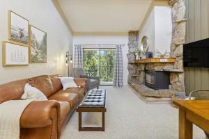 a living room with a leather couch and a fireplace at Cozy Winter Park Condo Bike, Ski, and Hike! in Winter Park