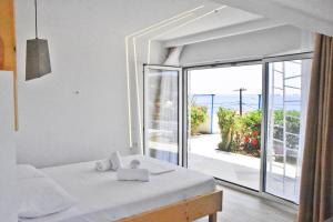 a white bedroom with a bed and a large window at Euripidean View, Apartments in Salamina