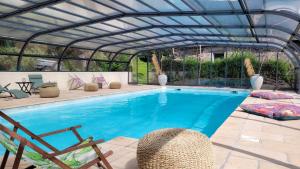 een zwembad met een metalen dak en een zwembadklep bij Manoir des Pélies in Conques