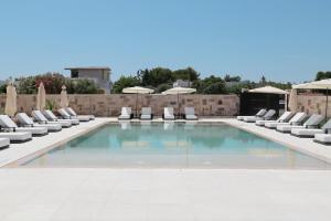 einen Pool mit Stühlen und Sonnenschirmen in der Unterkunft Salento Winery Lodge in San Pietro in Bevagna