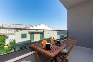 einen Holztisch auf einem Balkon mit Orangensaft in der Unterkunft New Apartment White Angel in Duće