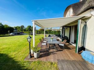 a patio with a table and chairs under a canopy at Vakantiehuis aan het water in Friesland in De Rijlst