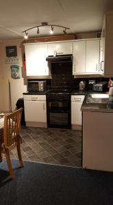 a kitchen with white cabinets and black appliances at 20 The Manor, Penstowe Holiday Park, Kilkhampton BUDE in Kilkhampton