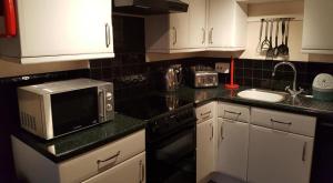 a kitchen with a microwave and a sink in it at 20 The Manor, Penstowe Holiday Park, Kilkhampton BUDE in Kilkhampton
