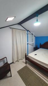 a bedroom with a bed and a chair and a window at Enjoy the Island - Rua do Negrão in Ponta Delgada