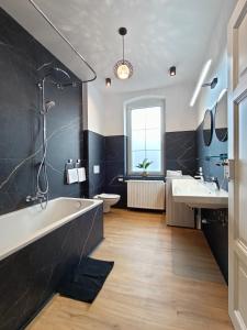 a bathroom with a tub and two sinks and a toilet at Ferienwohnung Coburg, familienfreundlich und stilvoll in Coburg