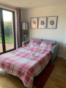a bedroom with a bed with a red and white plaid blanket at The Garden Room - Nature Stay in Suckley