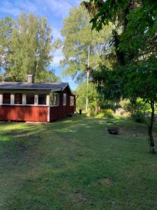 una cabina roja en medio de un patio en Sjönära stuga en Norrtälje
