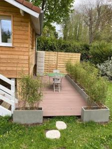 una terraza de madera con mesa y sillas en un patio en Au Bord de l'Oise, en Auvers-sur-Oise