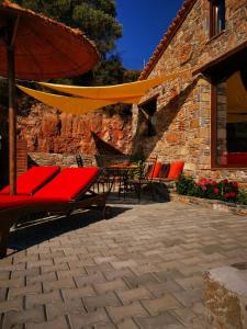 a patio with chairs and an umbrella and a table at Casa Romantica in Petriaí