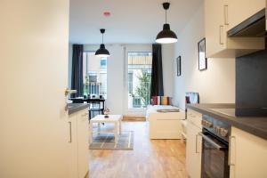 a kitchen with white cabinets and a living room at Flat2go modern apartments - Harmony of city and nature in Vienna