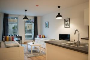 a kitchen and a living room with a couch at Flat2go modern apartments - Harmony of city and nature in Vienna