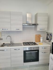 a kitchen with white cabinets and a stove top oven at Bilocale Lungomare Carini in Carini