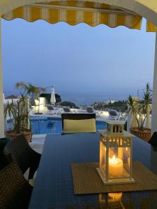 een kaars op een tafel op een patio met een zwembad bij 2 bedrooms villa with sea view private pool and furnished terrace at Benalmadena 2 km away from the beach in Benalmádena