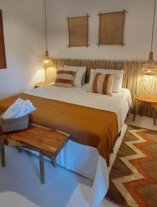 a bedroom with a large bed and a table at Afeto Caraíva in Caraíva