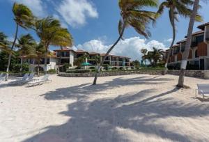 un resort con palme e sedie sulla spiaggia di Beach Living at Villas Pappagallo BLES a West Bay