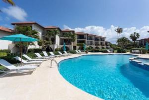 una piscina con sedie a sdraio e un resort di Beach Living at Villas Pappagallo BLES a West Bay