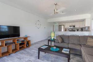 ein Wohnzimmer mit einem Sofa und einem Flachbild-TV in der Unterkunft Beach Living at Villas Pappagallo BLES in West Bay