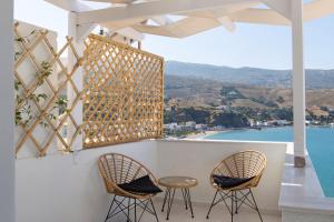 2 sillas y mesa en un balcón con vistas en ISTION ANDROS LUXURY SUITES, en Ándros