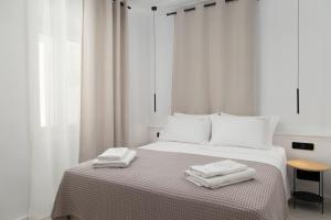 a white bedroom with two towels on a bed at ISTION ANDROS LUXURY SUITES in Andros