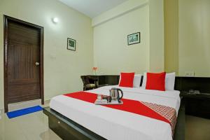 ein Hotelzimmer mit einem großen Bett mit roten Kissen in der Unterkunft OYO Tableau Homestay in Kandāghāt