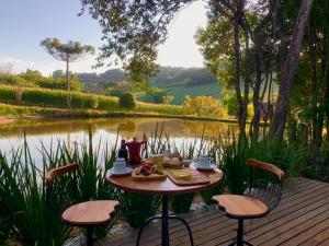 una mesa con comida sentada en una terraza junto a un lago en Cabana Vinhedos en Bento Gonçalves