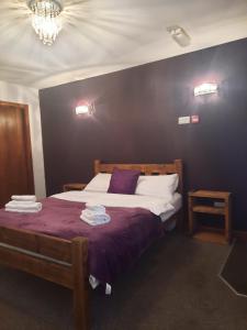 a bedroom with a large bed with a purple blanket at The Gardeners Country Inn in Goxhill